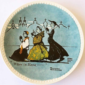 May include: A blue and white ceramic plate with a cartoon illustration of three people walking in a line. The people are wearing different religious clothing. The plate has the text "When in Rome" and the artist's signature "Norman Rockwell".