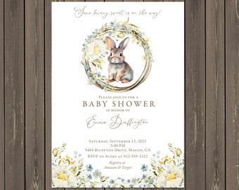 Könnte beinhalten: Eine Babyparty-Einladung mit einer Aquarell-Illustration eines Kaninchens in einem Kranz aus blauen und weißen Blumen. Der Text lautet "Same bunny sweet is on the way!" und enthält die Details der Party, einschließlich Datum, Uhrzeit, Ort und RSVP-Informationen.