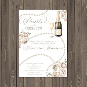 May include: A bridal shower invitation card featuring a watercolor illustration of a champagne bottle, a glass of prosecco, strings of pearls, and beige floral accents. The text reads Pearls and Prosecco, Join us to toast the bride to be at a bridal shower honoring Amanda Townsend, Saturday, August 10, 2024, 6:00 PM, 5464 Five Forks Drive, Lilburn, GA, RSVP to Amy at 470-555-1212, Registered at Amazon, Pottery Barn & Theknot.com.