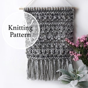 May include: Knitting pattern for a gray wall hanging with fringe. The wall hanging is made with a textured stitch and has a simple, modern design.