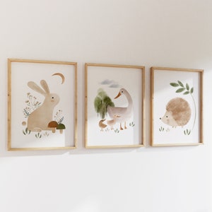 May include: Three framed illustrations of woodland animals. The first frame shows a brown rabbit sitting on a mushroom. The second frame shows a gray duck with a smaller duckling. The third frame shows a brown hedgehog with green leaves.