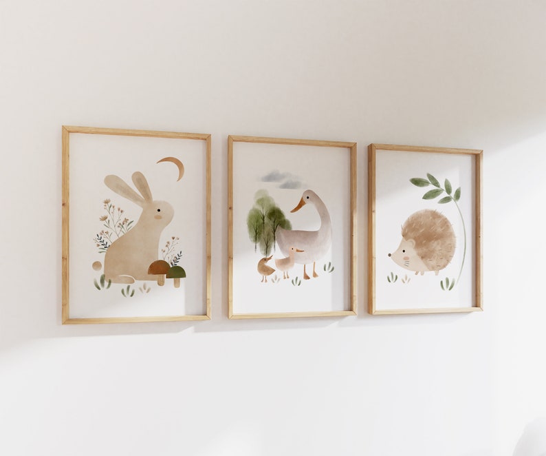 May include: Three framed illustrations of woodland animals. The first frame shows a brown rabbit sitting on a mushroom. The second frame shows a gray duck with a smaller duckling. The third frame shows a brown hedgehog with green leaves.
