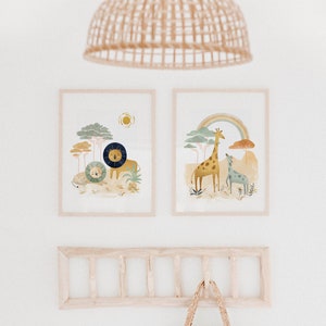 May include: Two framed illustrations of animals in a jungle setting. The left illustration features a lion and a smaller lion cub. The right illustration features a giraffe and a smaller giraffe. Both illustrations have a rainbow and trees in the background.