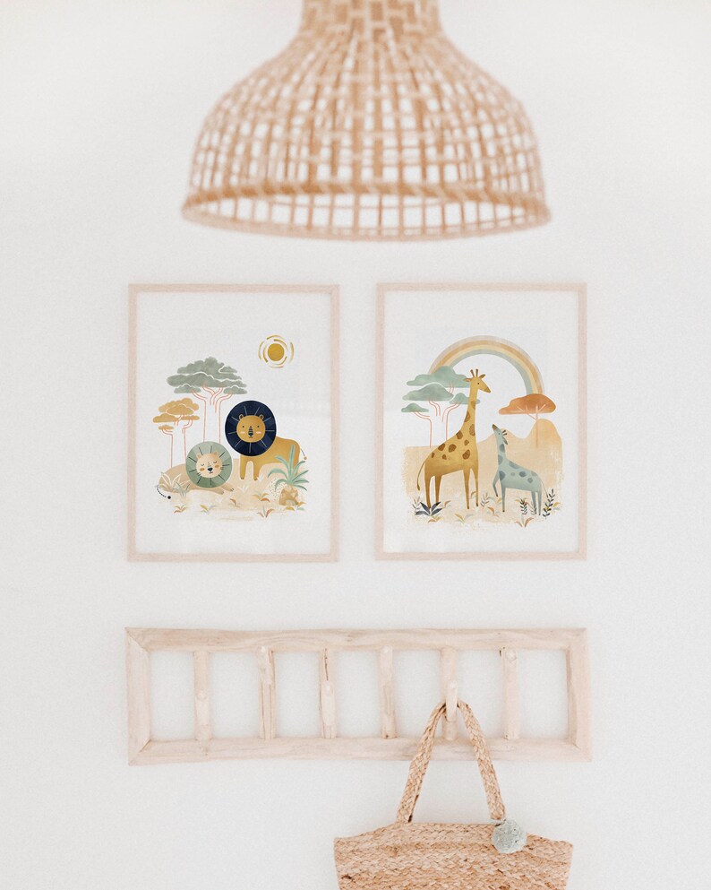 May include: Two framed illustrations of animals in a jungle setting. The left illustration features a lion and a smaller lion cub. The right illustration features a giraffe and a smaller giraffe. Both illustrations have a rainbow and trees in the background.