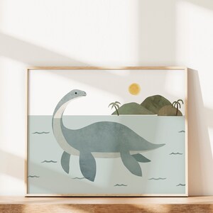 May include: A framed illustration of a blue plesiosaur swimming in a turquoise ocean with a small island in the background. The sun is shining in the sky above the island.