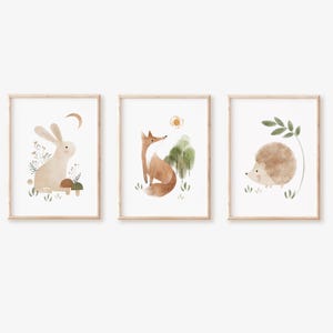 May include: Three watercolor illustrations in wooden frames, each featuring a different woodland animal: a rabbit, a fox, and a hedgehog. The illustrations are set against a neutral background with subtle green and brown accents.