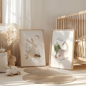 May include: Two framed illustrations of animals in a nursery setting. The first illustration features a white rabbit with brown accents sitting in a field of green grass and flowers. The second illustration features a white duck with brown accents and a smaller duckling in a field of green grass and trees.