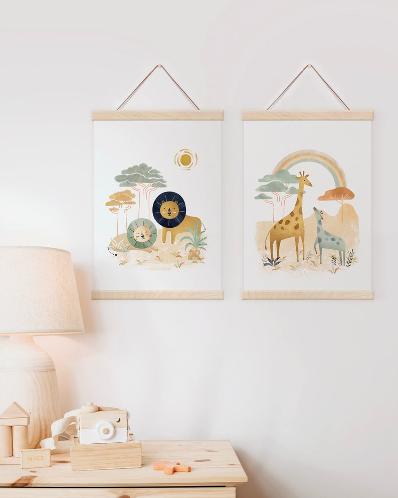May include: Two framed prints with a nature theme. The print on the left features a lion and a lion cub in a jungle setting with a sun in the background. The print on the right features a giraffe and a baby giraffe in a jungle setting with a rainbow in the background.