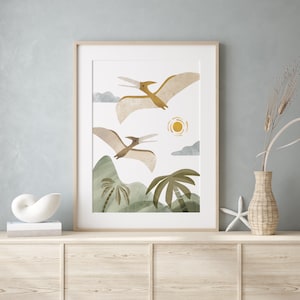May include: A framed print of two brown pterodactyls flying over a green landscape with palm trees and a yellow sun. The print has a white background.