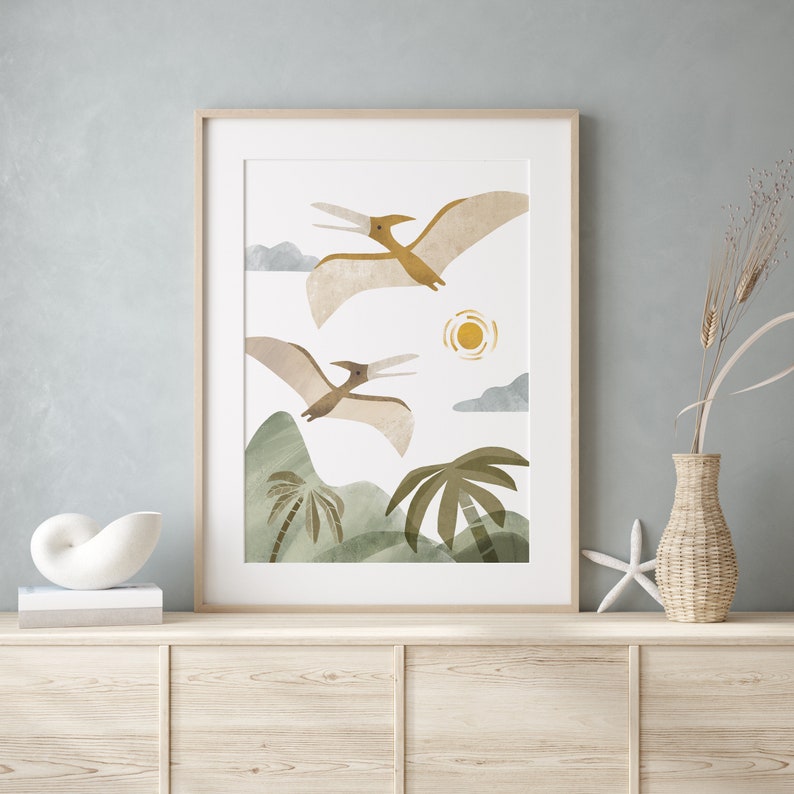 May include: A framed print of two brown pterodactyls flying over a green landscape with palm trees and a yellow sun. The print has a white background.