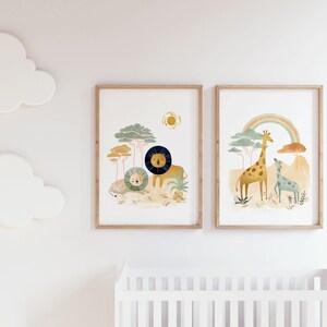 May include: Two framed illustrations of animals in a jungle setting. The first illustration features a lion and a lion cub in a green and brown jungle with a yellow sun. The second illustration features a giraffe and a smaller giraffe in a green and brown jungle with a rainbow.