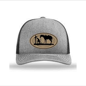 May include: A gray and black trucker hat with a brown oval patch featuring a silhouette of a person kneeling next to a horse. The patch has a rope design around the edge.