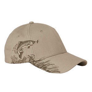 May include: A beige baseball cap with an embroidered image of a fish jumping out of the water. The fish is brown and has a white belly. The cap has a brown brim and a brown strap.
