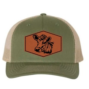 May include: A green and tan trucker hat with a brown leather patch featuring a black silhouette of a cow's head.