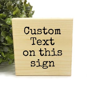 May include: A wooden sign with the text "Custom Text on this sign" in black lettering.