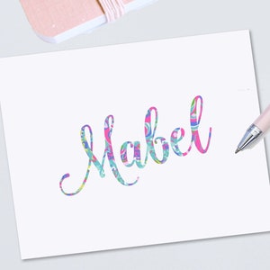May include: A white card with the name "Mabel" written in a colorful, patterned font.