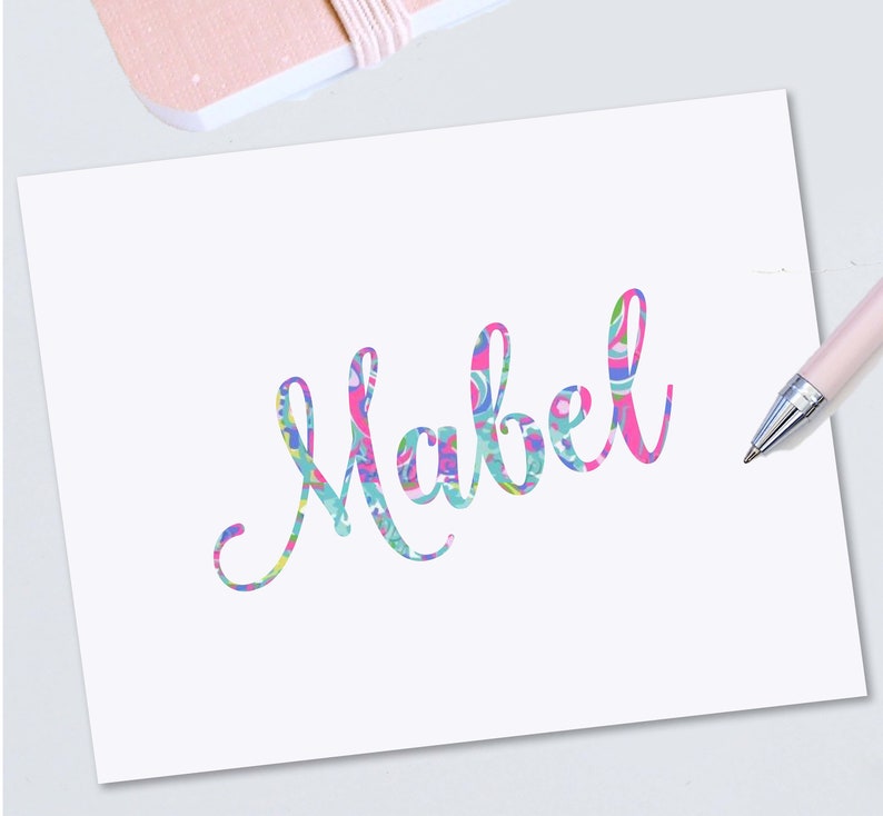 May include: A white card with the name "Mabel" written in a colorful, patterned font.