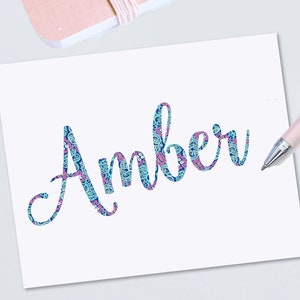 May include: A white card with the name "Amber" written in a blue and pink paisley pattern.