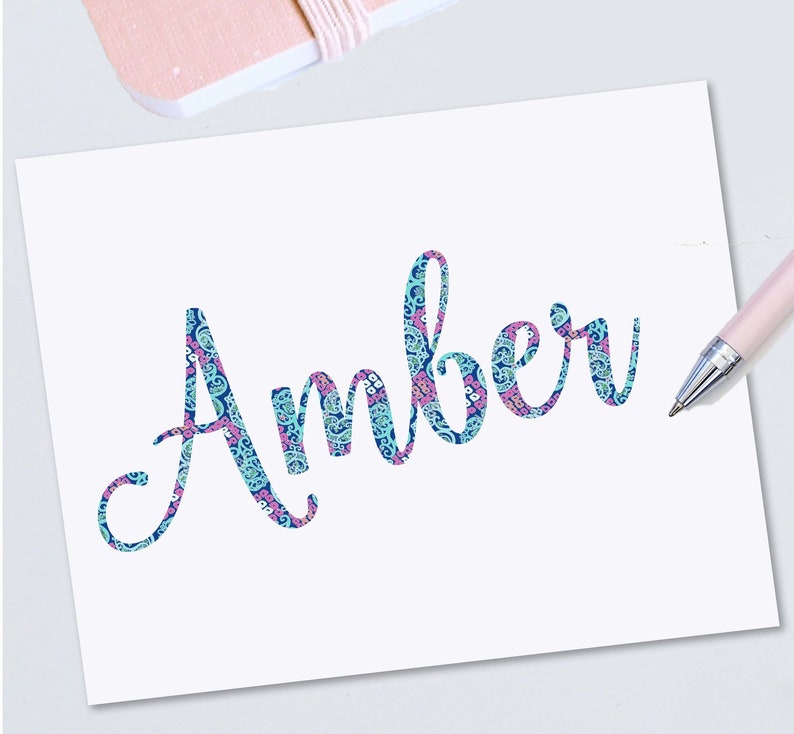 May include: A white card with the name "Amber" written in a blue and pink paisley pattern.