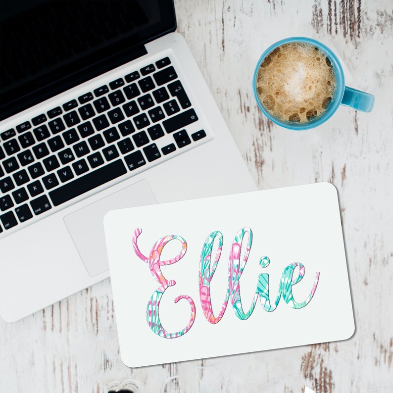 May include: White mousepad with the name "Ellie" written in a colorful, stylized font. The letters are filled with a pink, green, and orange floral pattern.