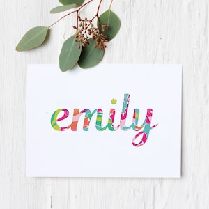 May include: A white card with the name "emily" written in colorful, patterned letters.