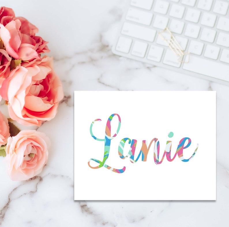 May include: A white card with the name "Lanie" written in colorful, stylized lettering. The letters are filled with a pattern of pink, blue, green, and orange.