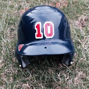 May include: A blue baseball helmet with a white and red number 10 on the front.