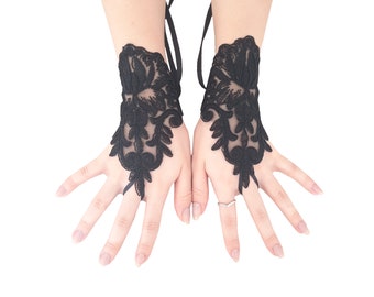 May include: A pair of black lace fingerless gloves with floral designs. The gloves have a wrist strap and are made of delicate lace.
