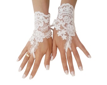 Puede incluir: Un par de guantes sin dedos de encaje blanco con un delicado patrón floral. Los guantes tienen una correa de muñeca y un bucle para el dedo para un ajuste seguro.