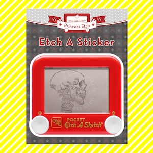 Puede incluir: Un juguete Etch A Sketch de plástico rojo con un dial blanco y un dibujo de una calavera en la pantalla. El texto "Pocket Etch A Sketch" está impreso en el juguete.