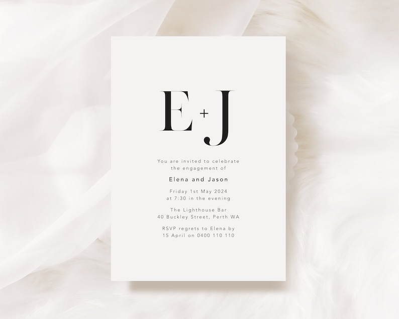 K&ouml;nnte beinhalten: Schlichte Verlobungskarte mit den schwarzen Initialen "E + J" in serifenbetonter Schrift. Der Text gibt die Namen Elena und Jason, Datum, Uhrzeit, Veranstaltungsort und RSVP-Informationen an.