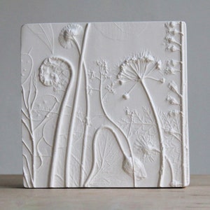 May include: White plaster wall art featuring a raised relief design of pressed botanicals, including leaves, stems, and flowers.