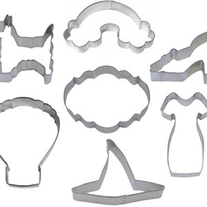 May include: Set of seven metal cookie cutters in various shapes, including a dog, a rainbow, a cloud, a dress, a shoe, a hat, and a seashell.