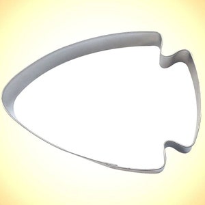 May include: A silver-colored metal arrowhead-shaped cookie cutter. The cutter has a smooth, curved design with a pointed tip and a notched base. The cutter is designed for baking and crafting.