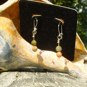 May include: A pair of silver dangle earrings with green and orange gemstone beads.