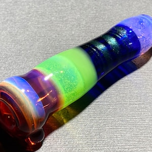 Op de afbeelding: Een meerkleurige glazen pijp met een kleurenschema van rood, paars, groen en blauw. De pijp is gemaakt van glas en heeft een glad, afgerond oppervlak.