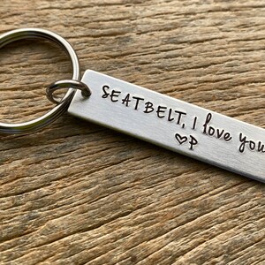 May include: Silver keychain with a rectangular tag that reads "Seatbelt, I love you" with a heart symbol.