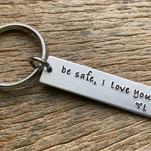 May include: Silver keychain with a rectangular tag that reads "be safe, i love you" with a heart symbol.