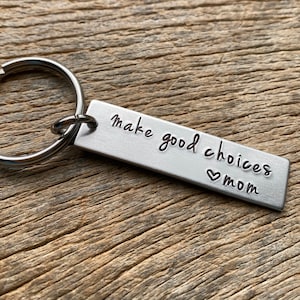 May include: Silver keychain with a rectangular tag that reads "make good choices ♥ mom".