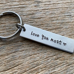 May include: Silver keychain with a rectangular tag that reads "love you most" with a small heart symbol.