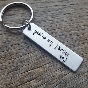 May include: Silver keychain with a rectangular tag that reads "you're my person" with a heart symbol.