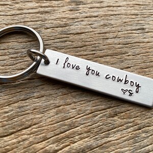 May include: Silver keychain with a rectangular tag that reads "I love you cowboy" with a heart symbol.