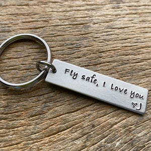 May include: Silver keychain with a rectangular tag that reads "Fly safe, I love you" with a heart symbol.