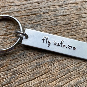 May include: Silver keychain with a rectangular tag that reads "fly safe. ♥ m".