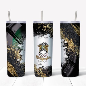 Könnte beinhalten: Drei Edelstahlbecher mit schwarzem und goldenem Glitzerdesign. Der mittlere Becher zeigt eine Grafik einer Frau mit einer Kamera und den Text "Photographer est."