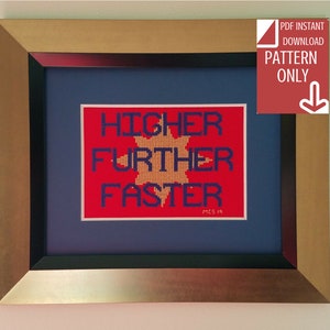 以下が含まれることがあります： 赤い背景と青い文字で「HIGHER FURTHER FASTER」と書かれた、黄色い星が中央にある、額縁に入ったクロスステッチのデザイン。文字は太字で、サンセリフ体。フレームは金色で、黒いマット付きです。