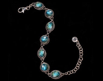 May include: A silver bracelet with a chain and six oval-shaped blue gemstones.