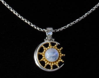 May include: A silver chain necklace with a crescent moon pendant featuring a white moonstone surrounded by a gold sunburst design.
