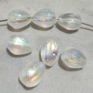 May include: A collection of iridescent glass beads in various shapes and sizes. The beads have a pearlescent finish and are perfect for jewelry making.