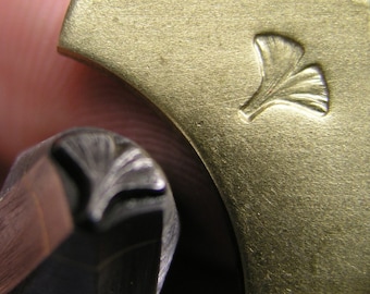 Op de afbeelding: Close-up van een metalen stempel met een ginkgo-bladontwerp. De stempel wordt gebruikt om indrukken in metaal te maken.